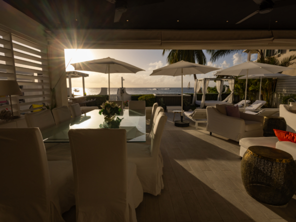 Barbados luxury modern beachfront villa with alfresco covered dining and lounge at sunset