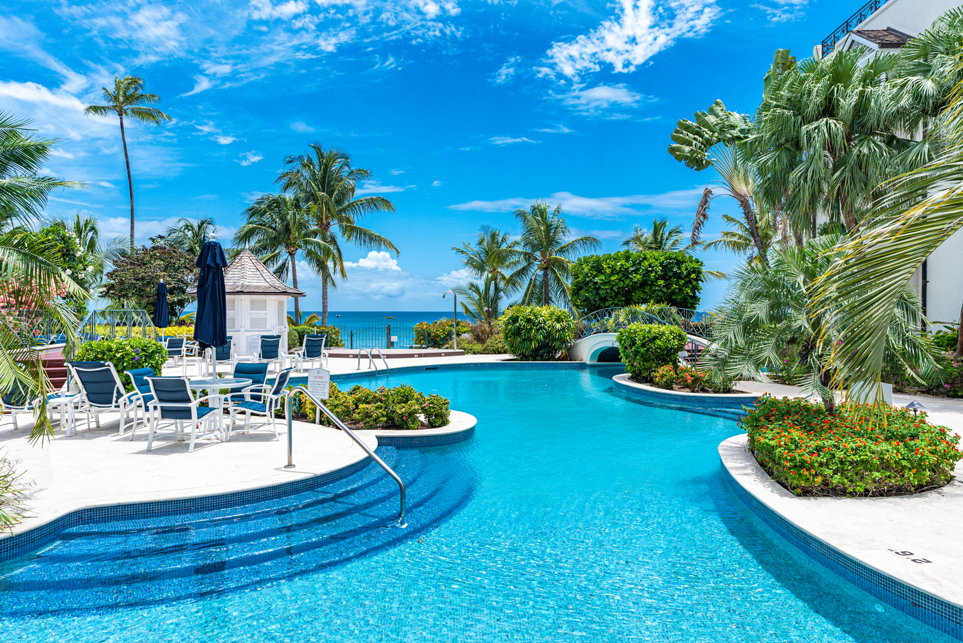 A large turquoise swimming pool in front of the ocean in Barbados