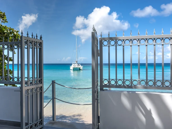 View through a grey beach gate at Caribbean Barbados beach house.