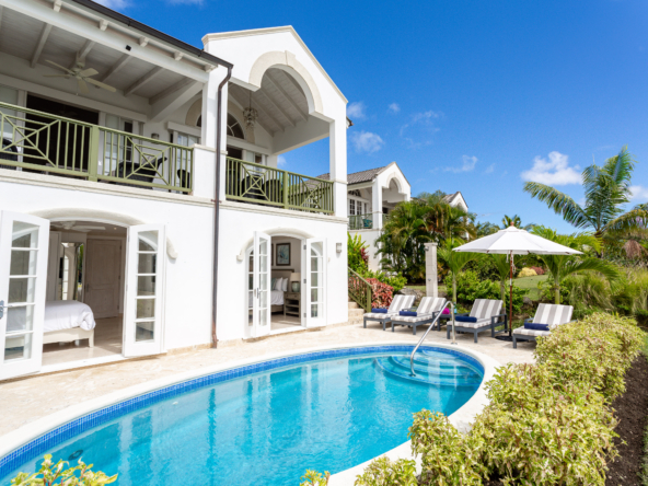 Exterior view of white villa, swimming pool, and blue sky at Royal Westmoreland Townhouse