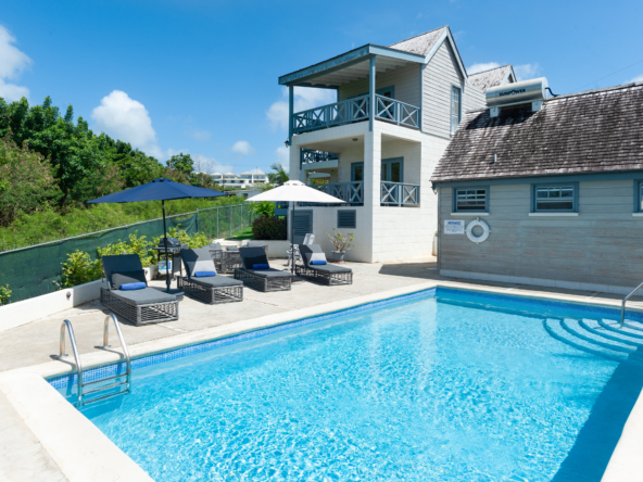 Exterior view of two bedroom villa, swimming pool, and blue sky at Westrock Villa