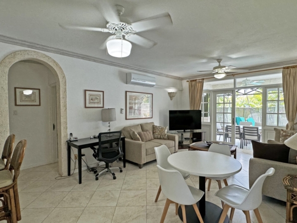 The dining room at Summerland101, a peaceful 3-bedroom villa near Sandy Lane, Barbados, features a cozy table setup surrounded by elegant decor and large windows that invite natural light, offering views of lush gardens for a serene dining experience.