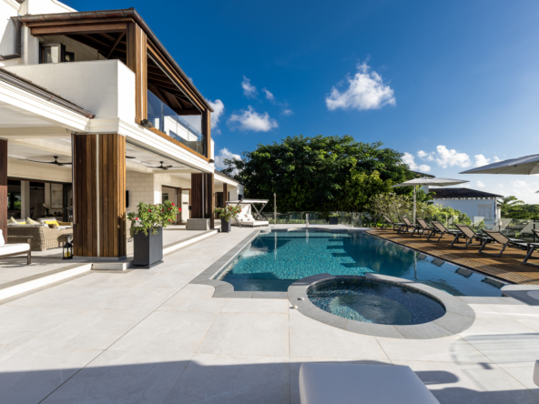 Exterior view of white villa, swimming pool, and blue sky at Royal Westmoreland Townhouse