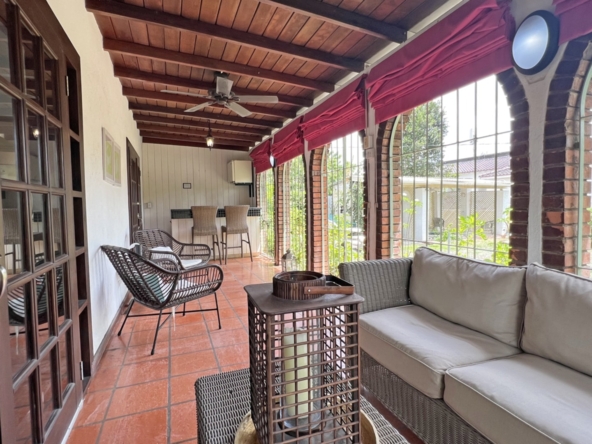 Image shows tranquil 3 Bedroom Villa-Las Palmas outdoor dining area at Las Palmas, featuring a spacious patio surrounded by lush tropical gardens and tall trees, perfect for relaxation or entertaining on Barbados' Platinum Coast.