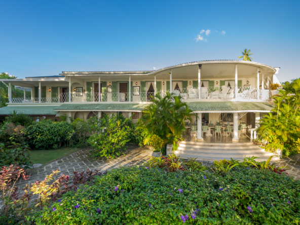 Image showing the exterior of a magnificent beachfront villa, featuring a stunning modern design with expansive windows, lush tropical landscaping, and a breathtaking view of the ocean in the background.