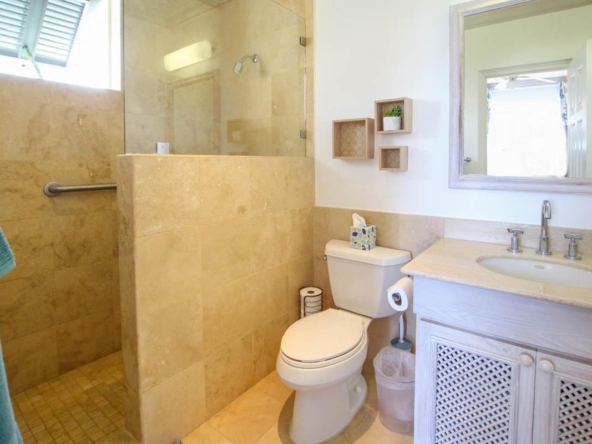 Elegant 2-bed ocean view condo for sale in Barbados' Beacon Hill, steps from Mullins Beach with rooftop pool and tropical gardens.
